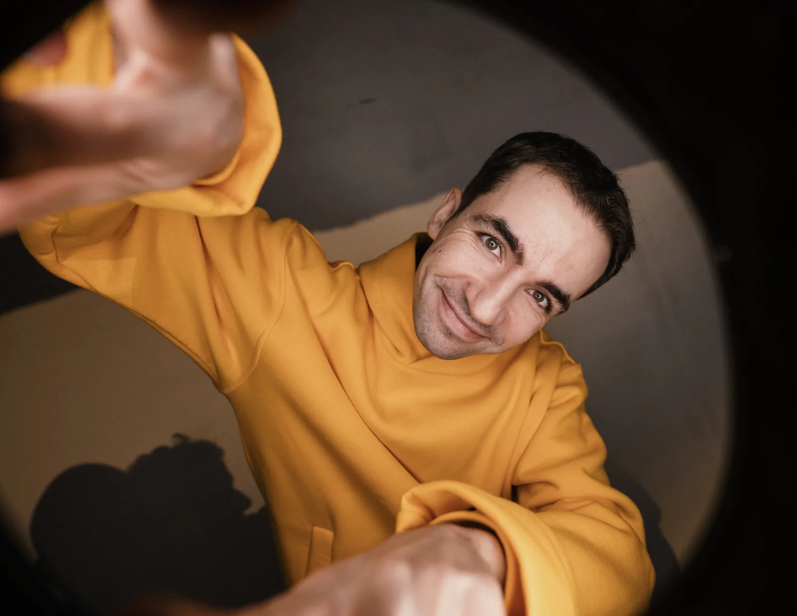 Tomas Banišauskas in a yellow hoodie grinning up at the camera