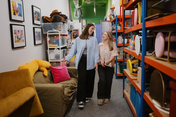 Two colleagues laughing as they walk through the props room